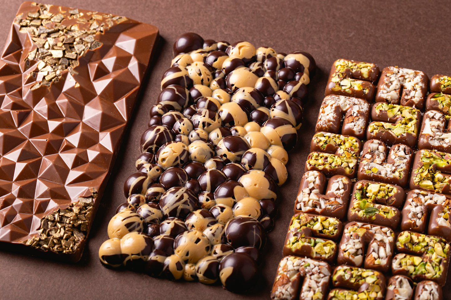 Gourmet chocolate bars and squares arranged on a brown surface.