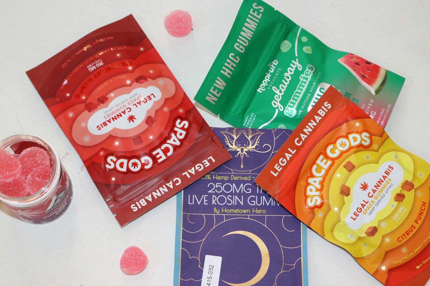 Four colorful gummy packages and a jar of heart-shaped candies.