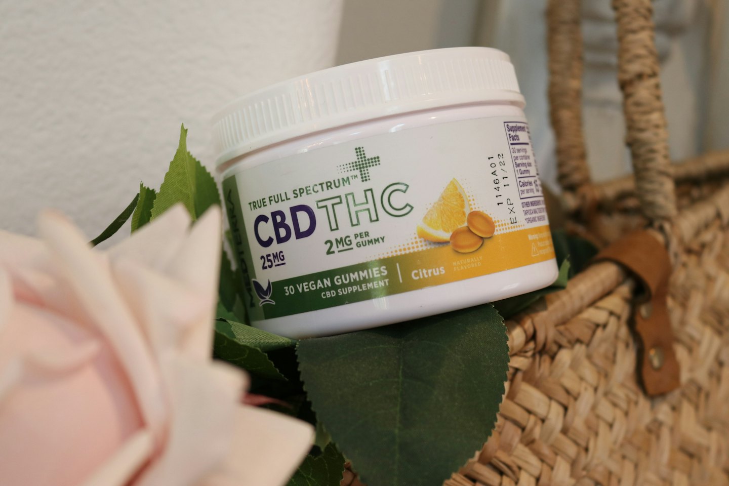 Container of True Full Spectrum CBD THC gummies on green leaves.