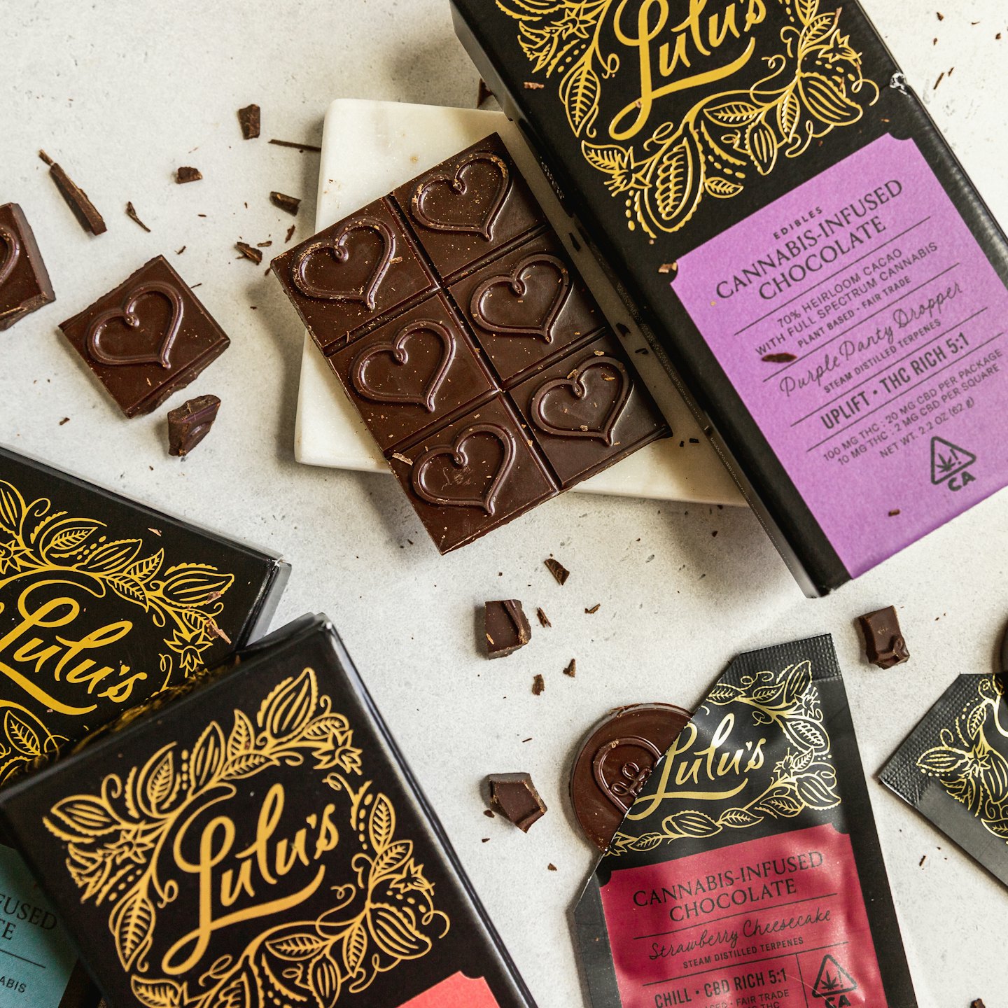 Cannabis-infused chocolate bars and pieces on a grey surface.