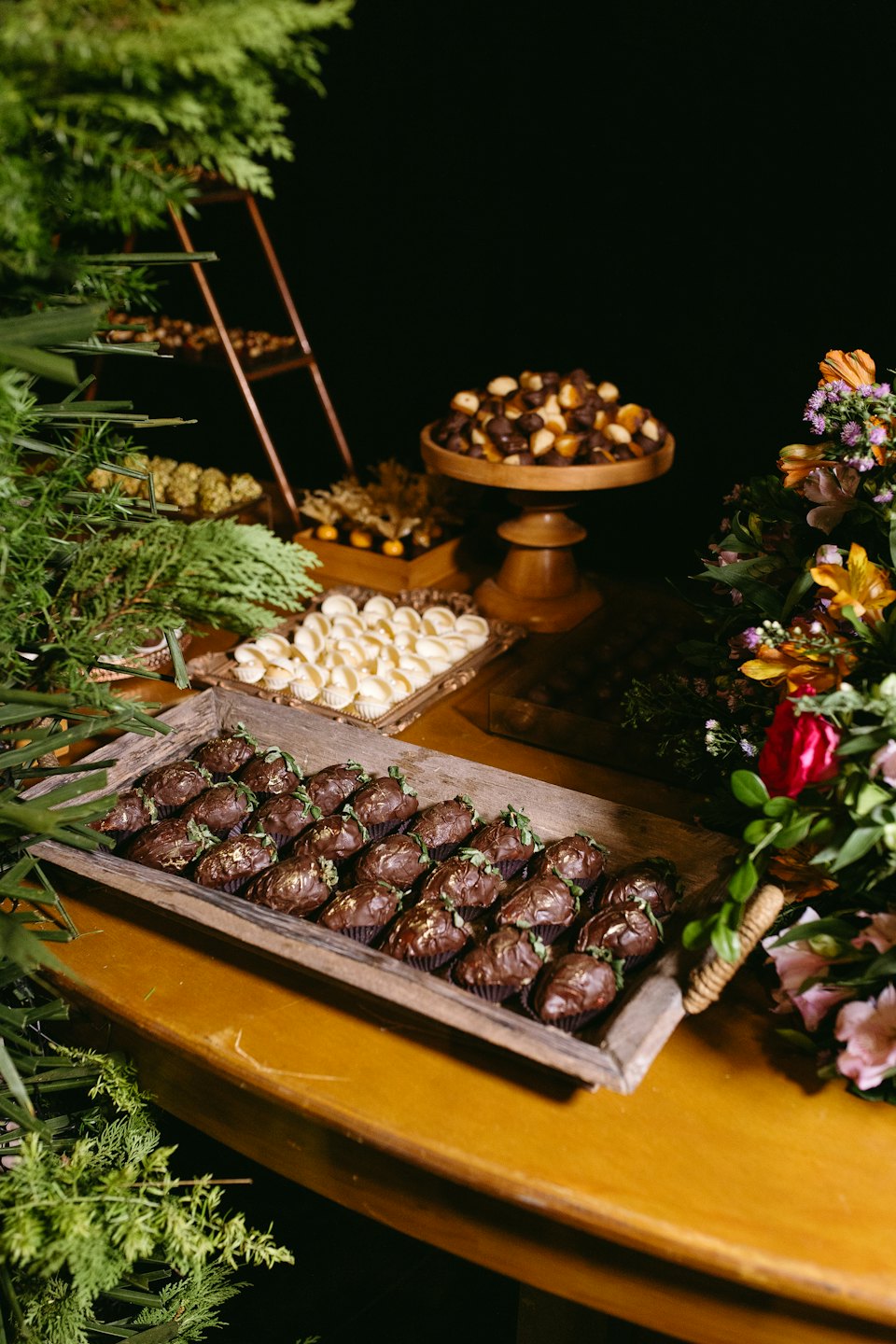 Gourmet chocolate desserts arranged on a rustic wooden table with greenery.