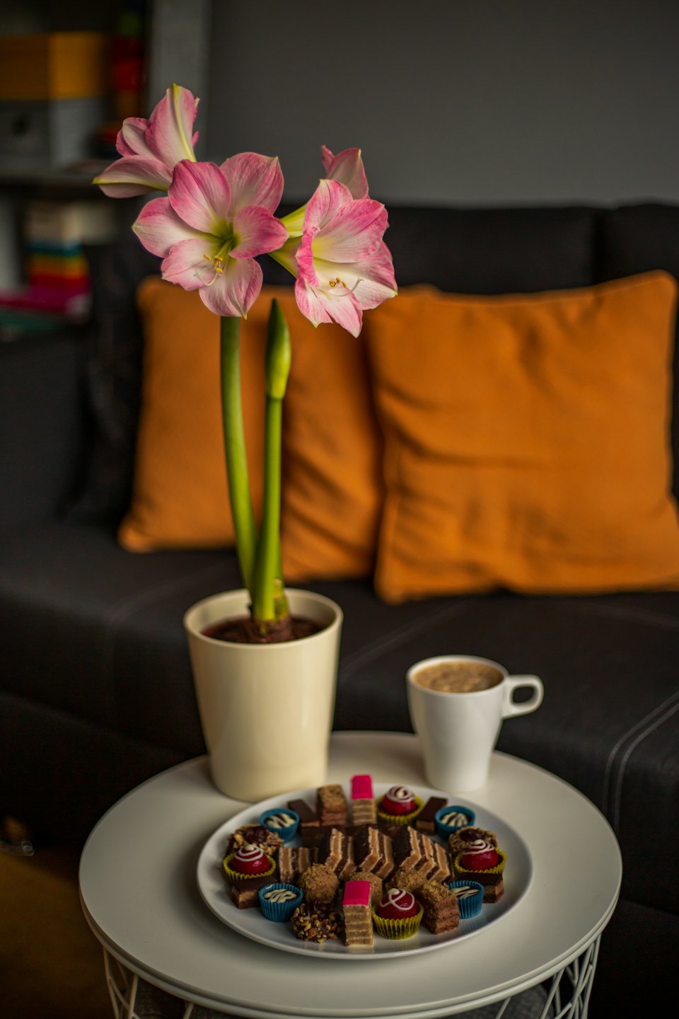 Miniature pastries and chocolates sit beside coffee and a flower.