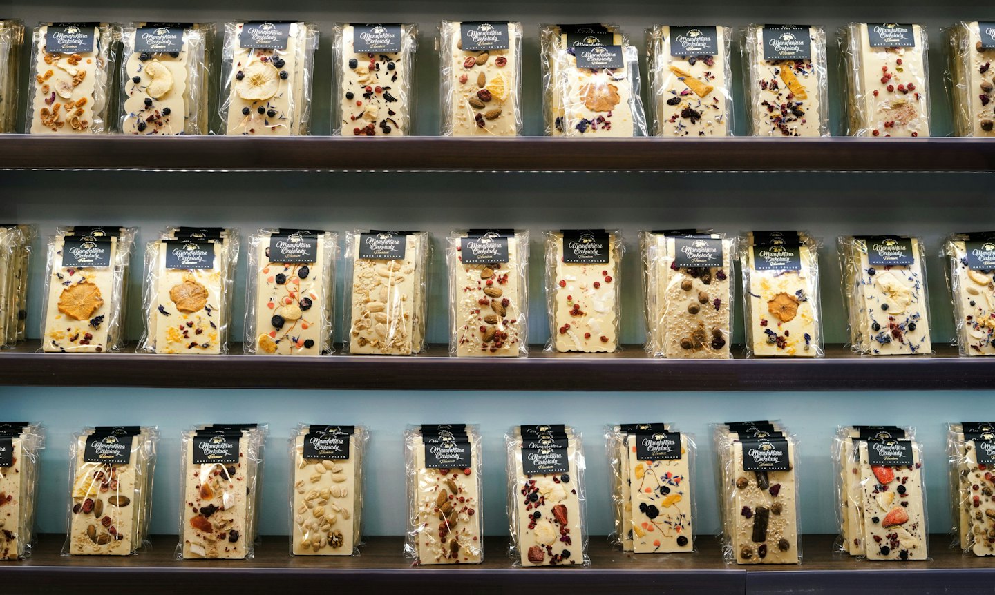 Artisanal white chocolate bars with fruit and nuts on shelves.